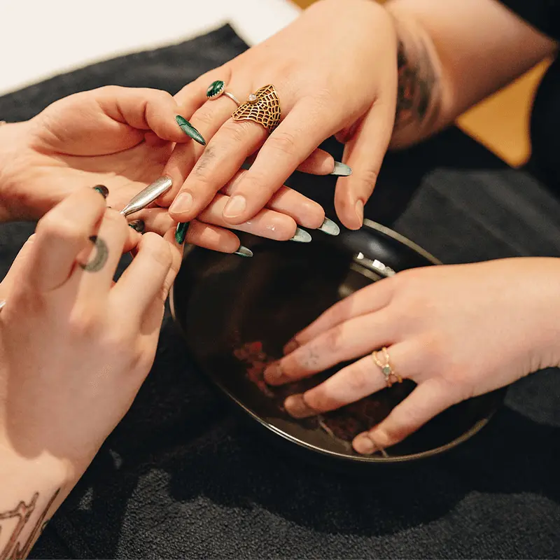 Client soaking hand in manicure bowl and getting cuticle work